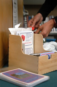 Image of wooden box containing buisiness cards and props for the project on library desk with hands in background